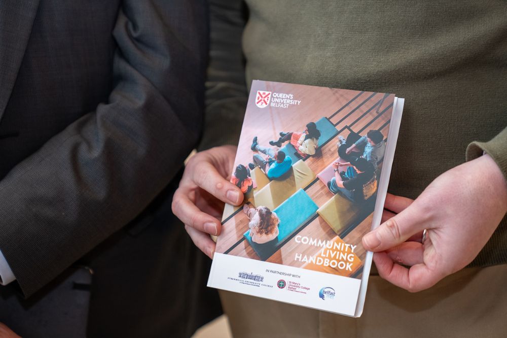 Close-up of someone holding the Queen’s University Belfast Community Living Handbook.