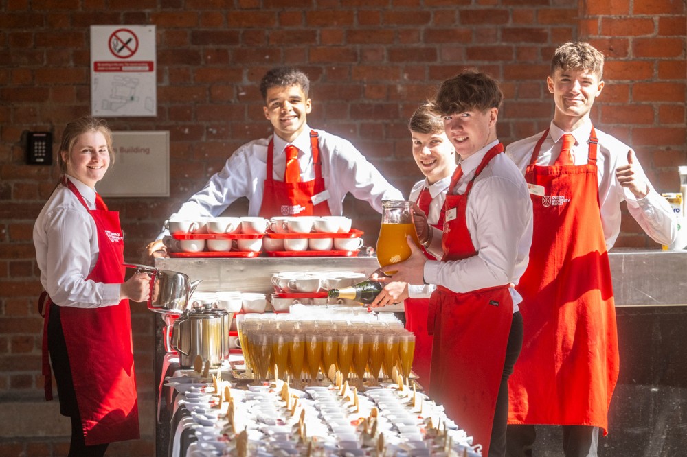 group of young catering staff standing at a catering table in a sheltered outdoor area