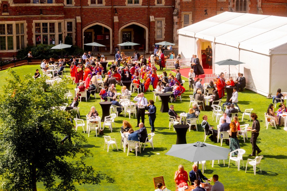 elevated view of a graduation party, including white gazebo, taking place on the inner quadrangle lawn of a redbrick building