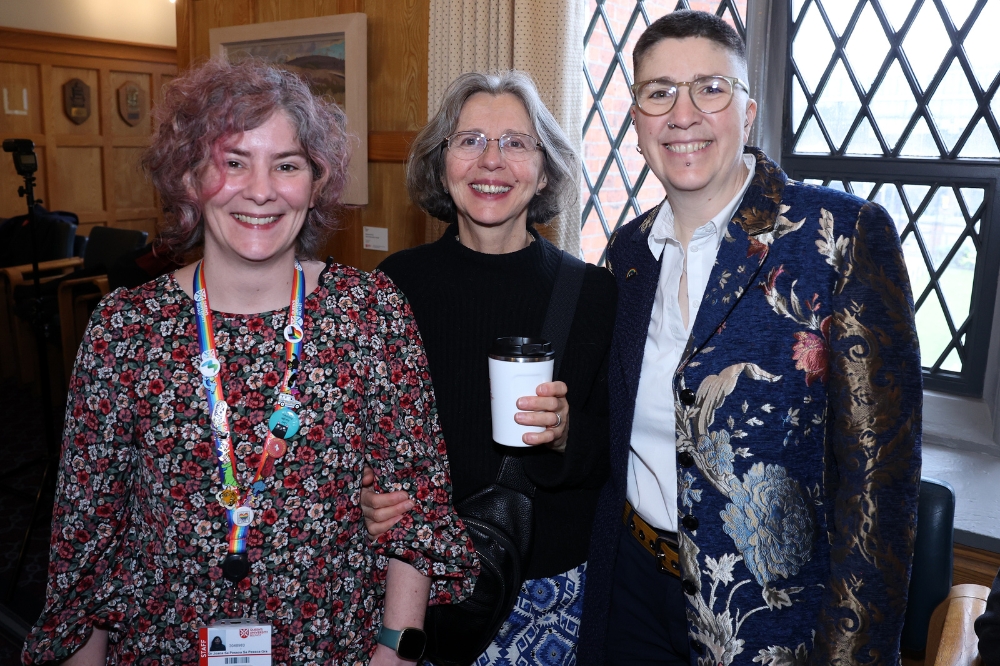 A group of people standing together indoors, smiling and posing for a photo in front of a wall.