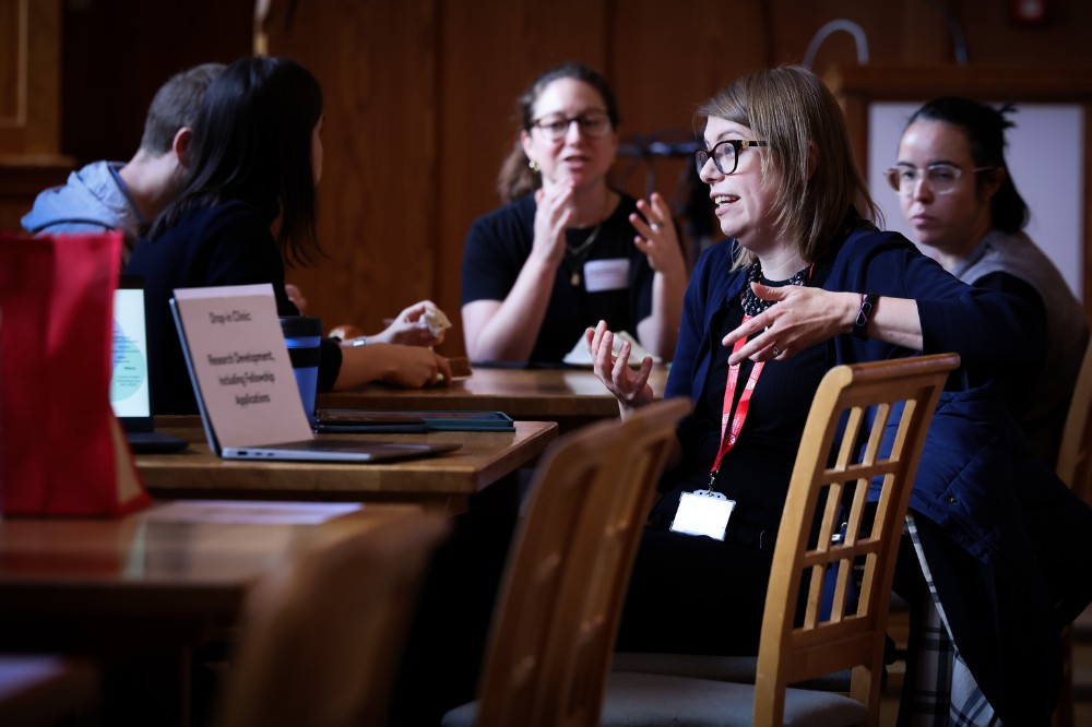 four seated women conversing in a somewhat darkened event space