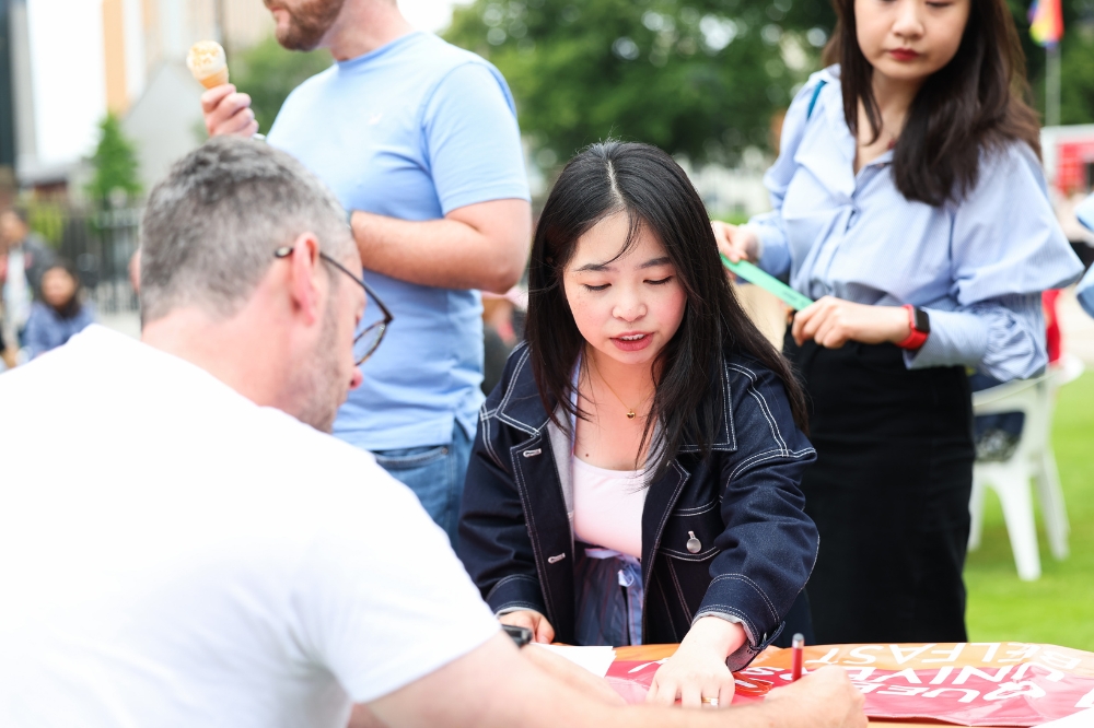 two young women of East Asian origin at an outdoor event registration table