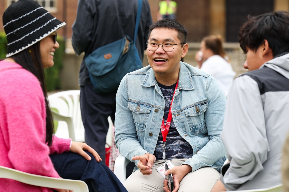 three seated young people of Asian origin chatting at an outdoor event