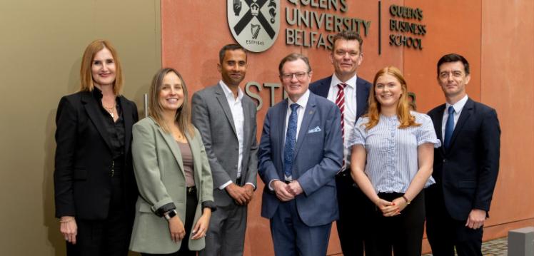 group of people standing infront of Queen's Business School