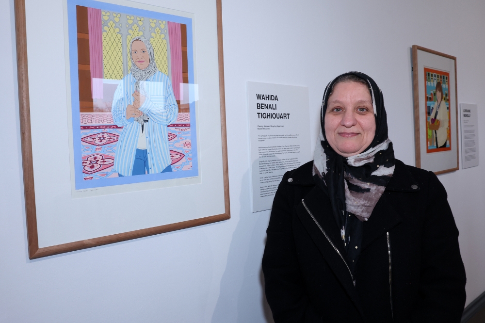 Nominee Wahida Benali Tighiouart standing in front of her portrait in the Naughton Gallery