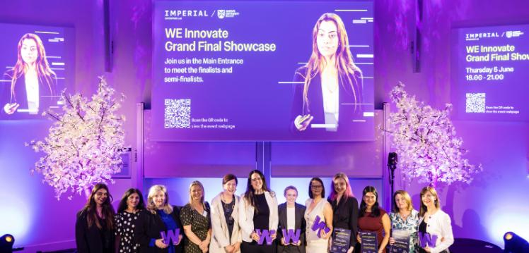 A group of female entrepreneurs stand under a large screen holding awards
