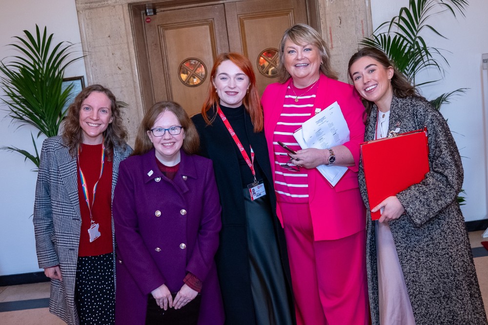 five women in warm clothing smiling to camera in the foyer area of an event hall