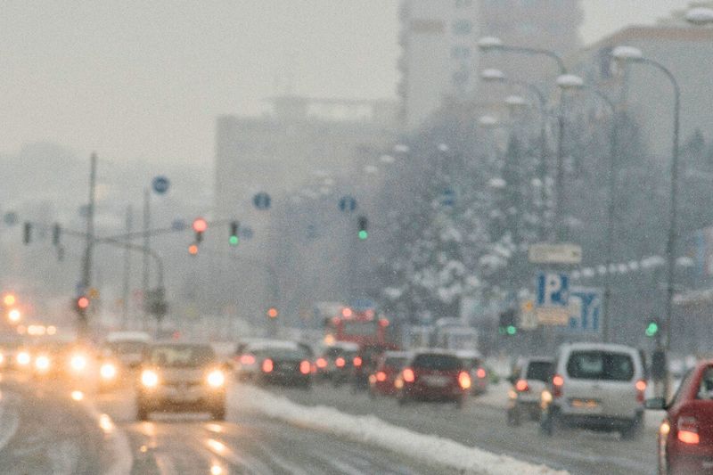cars driving outside a city on a busy wintry road on a dull day
